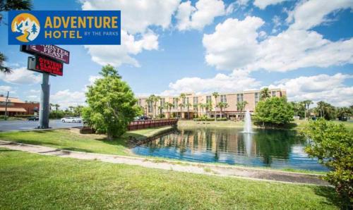 a sign for a hotel with a pond in front of a building at The Adventure Hotel by the Parks in Orlando