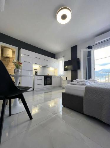 a white bedroom with a bed and a kitchen at Mediterranean Port Suite in Ágios Rókkos