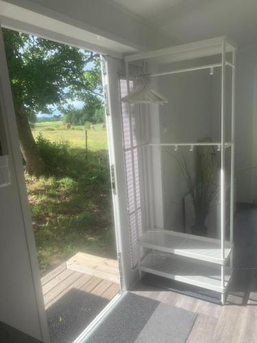 an open glass door with a view of a field at Cozy accommodation on horse farm in Alunda
