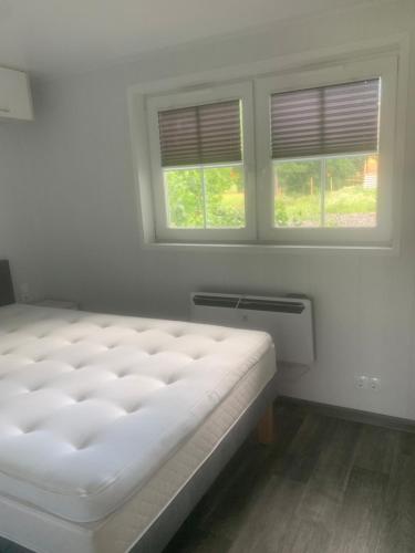 a white bed in a room with two windows at Cozy accommodation on horse farm in Alunda
