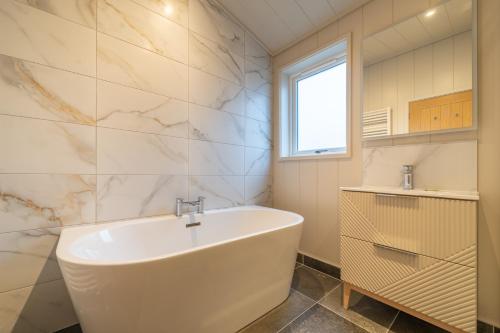 a bathroom with a white tub and a window at Park Lodge in Penrith