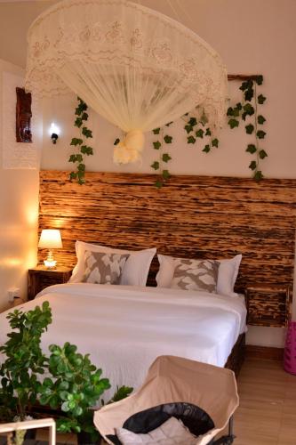 a bedroom with a white bed with a wooden headboard at Peryn Suites Kinubi, Hoima City, Uganda in Hoima