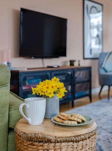 a coffee table with a plate of cookies and a tv at Seaside 2Bed En-suite Flat, Parking by Adliv in Margate
