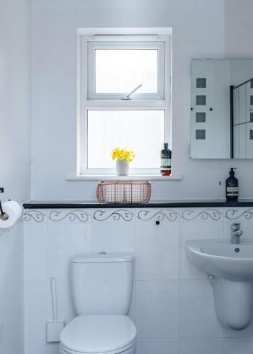 a white bathroom with a toilet and a window at Seaside 2Bed En-suite Flat, Parking by Adliv in Margate