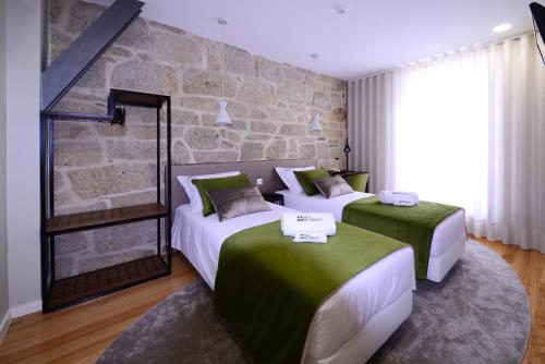 two beds in a room with a stone wall at VILA DE PONTE GUEST HOUSE in Ponte de Lima