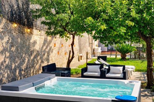 a hot tub in a yard with chairs and trees at Eden Holiday in Minori