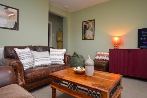 a living room with leather couches and a coffee table at Dunmore Coastal Retreat in Dunoon