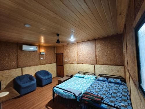 a bedroom with a bed and two blue chairs at victory farms in Nadora