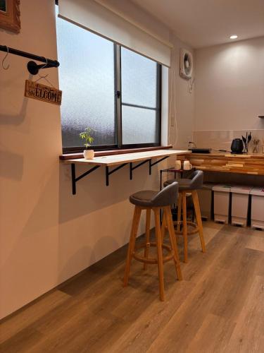 a kitchen with two stools and a counter with a window at 細島 Base Clutch in Hyuga