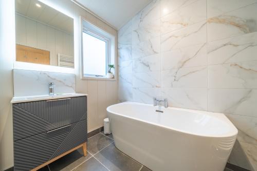 a bathroom with a tub and a sink and a mirror at Barton Lodge in Penrith
