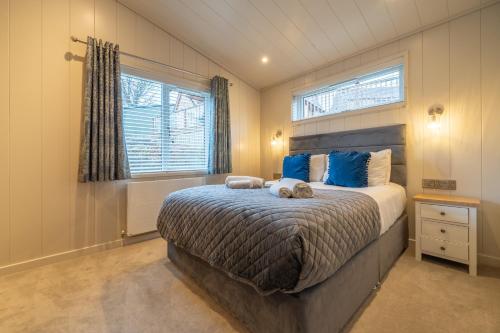 a bedroom with a bed with blue pillows and a window at Barton Lodge in Penrith
