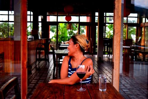a woman sitting at a table with a glass of wine at Guerrera Rice Paddy Villas in Mambajao