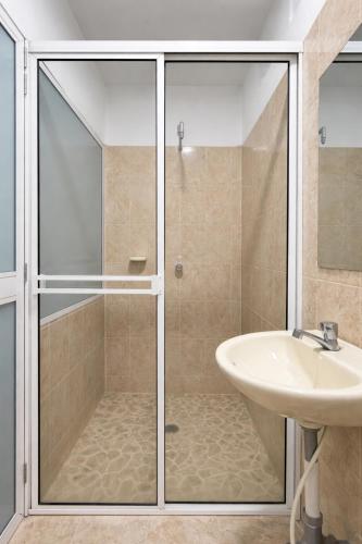 a bathroom with a glass shower and a sink at Hotel Babilonia Boutique in Cúcuta