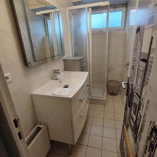 a white bathroom with a sink and a shower at Chez Albert au bord de plage in Cherrueix
