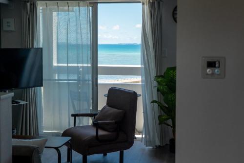 a living room with a chair and a view of the ocean at Crest Blue 402-オーシャンフロント! 新築マンション! in Kin
