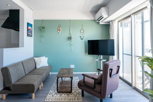 a living room with a couch and a tv at Crest Blue 402-オーシャンフロント! 新築マンション! in Kin