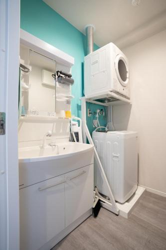 a bathroom with a sink and a washing machine at Crest Blue 402-オーシャンフロント! 新築マンション! in Kin