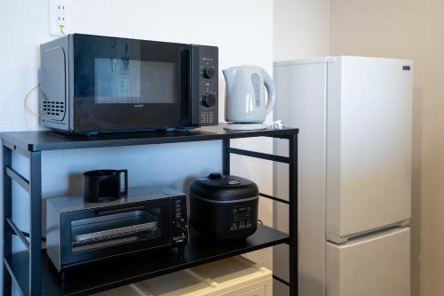 a microwave and a refrigerator on a shelf next to a microwave at Crest Blue 402-オーシャンフロント! 新築マンション! in Kin