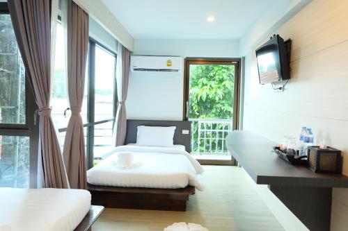 a bedroom with two beds and a tv and a window at A Plus Deluxe Hotel in Ko Lipe