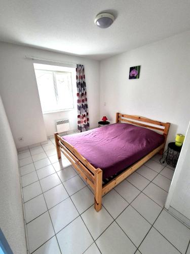 a bedroom with a wooden bed with a purple blanket at Gîte La Vallée RDC Neyrac-les-Bains in Meyras