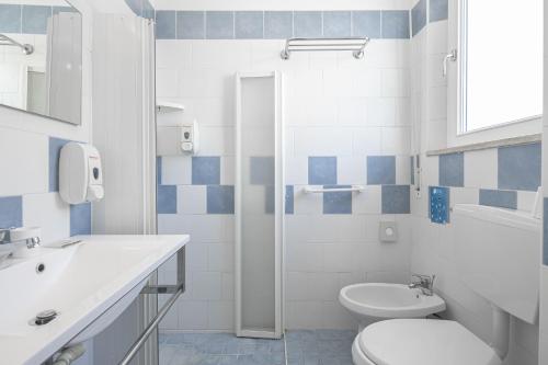 a white bathroom with a toilet and a sink at Hotel Rudy Cervia in Cervia