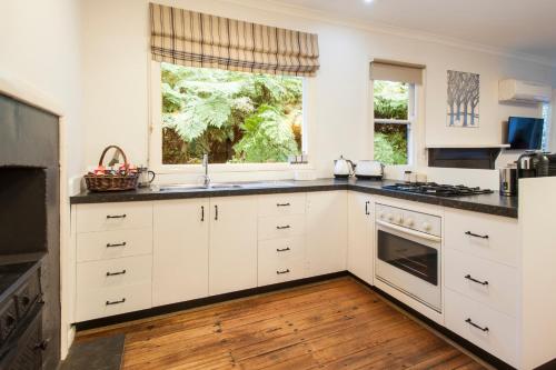 eine Küche mit weißen Schränken, einem Waschbecken und einem Fenster in der Unterkunft Cottage in the Forest in Olinda