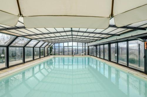 an indoor swimming pool with glass walls and a ceiling at Villa Fefa by MMega in Tolentino