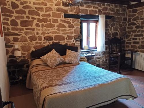 a bedroom with a bed with a stone wall at CASA RURAL MATÉ in Susilla