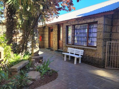 a white bench sitting outside of a building at Sandstone Escape Guesthouse in Ladybrand