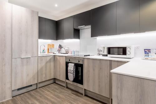 a kitchen with stainless steel appliances and black cabinets at Once Upon a Tide - Stylish Apartment in the Heart of Poole in Poole