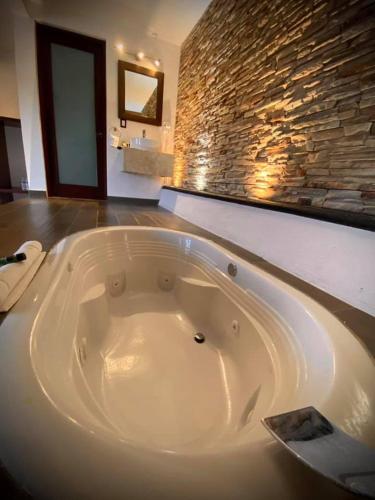 a large bath tub in a bathroom with a stone wall at Cabañas Rancho San Jorge in Bernal