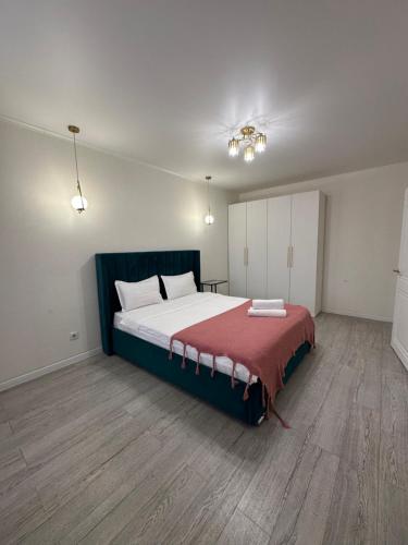 a bedroom with a large bed with a red blanket at Аблайхана 1 г in Kokshetau