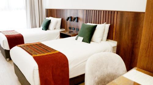 a hotel room with two beds with white and green at Maytaq Wasin Boutique Hotel in Cusco