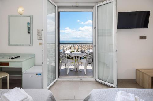 a bedroom with a balcony with a table and chairs at Hotel Rudy Cervia in Cervia