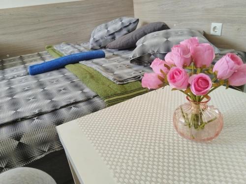 a vase filled with pink roses on a bed at City Centre Suits 3 in Varna City