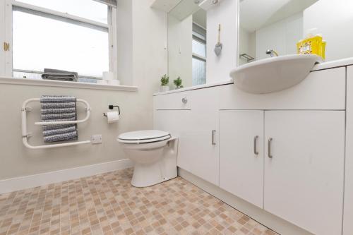 a white bathroom with a sink and a toilet at Lombard Hide Away in Inverness