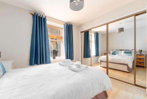 a bedroom with a large white bed and blue curtains at Lombard Hide Away in Inverness