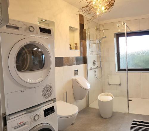 a bathroom with a toilet and a washing machine at Lilie in Weilmünster