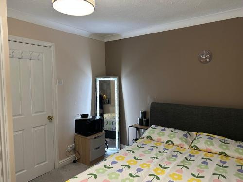 a bedroom with a bed and a window and a mirror at Comfy En-suite room in Gloucester
