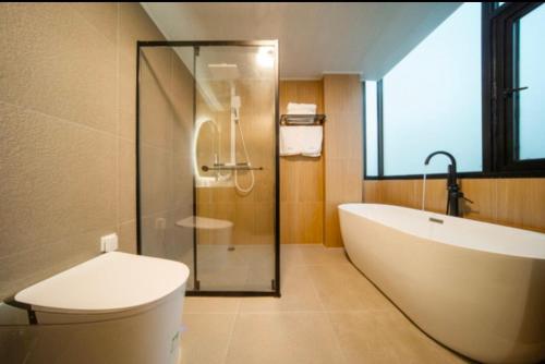 a bathroom with a tub and a toilet and a shower at 伴山一墅 in Chaoyang