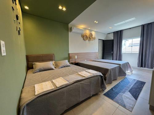 two beds in a room with green walls at Pousada Minas Gerais in Araxá
