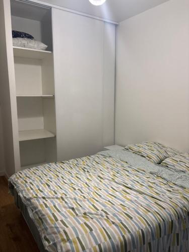 a bedroom with a bed and a white wall at Chambre privée dans un appartement partagé in Colombes
