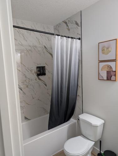 a white bathroom with a toilet and a shower at Granny's Hug, a cozy 2 Bedroom Basement Suite in Calgary