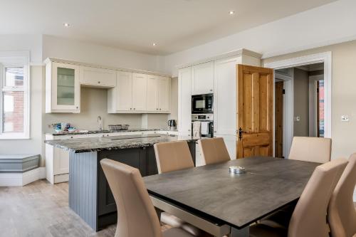 a kitchen with a table and chairs and a kitchen with white cabinets at Park Lake View - Poole Park Lake Views in Poole