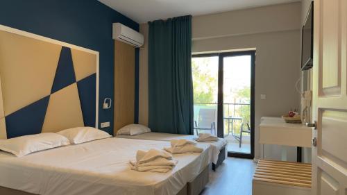 two beds sitting in a room with a window at Hotel ADMIRAL POTOS THASSOS in Potos