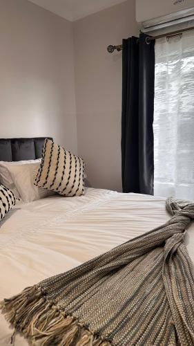 a bed with a blanket on it with a window at The F402 Residence in Gaborone