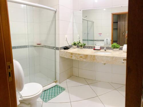a bathroom with a shower and a toilet and a sink at Cambuci Hotel in Camaçari