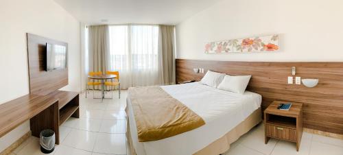 a hotel room with a large bed and a television at Cambuci Hotel in Camaçari