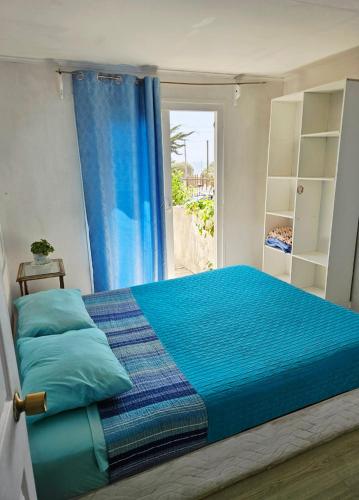 a bedroom with a bed with blue sheets and a window at Paioneal Hostel l Spa Jacuzzi Sauna in El Quisco