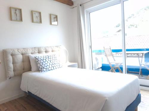 a white bedroom with a bed and a large window at Porto Pim Guest House in Horta